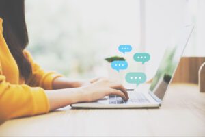 a woman types on her laptop, having a conversation via live chat.