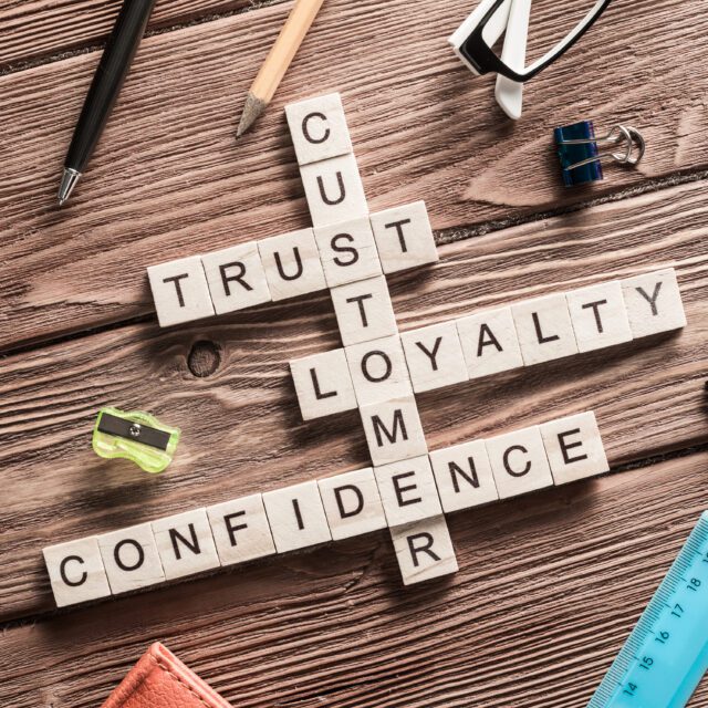 A selection of wooden cubes on a desk with letters on, spelling ‘customer’, ‘trust’, ‘loyalty’, and ‘confidence’.